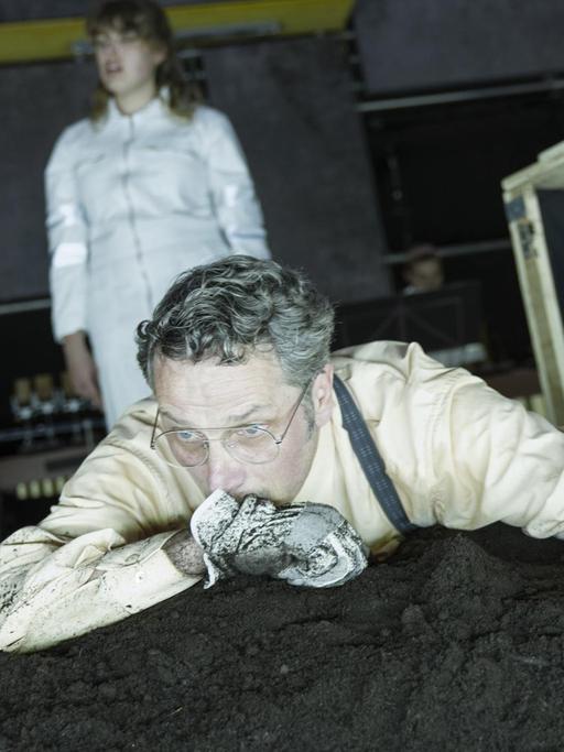 Ein Mann liegt auf einem Erdhaufen und guckt traurig. Uraufführung von "Alles klappt" im Residenztheater München.