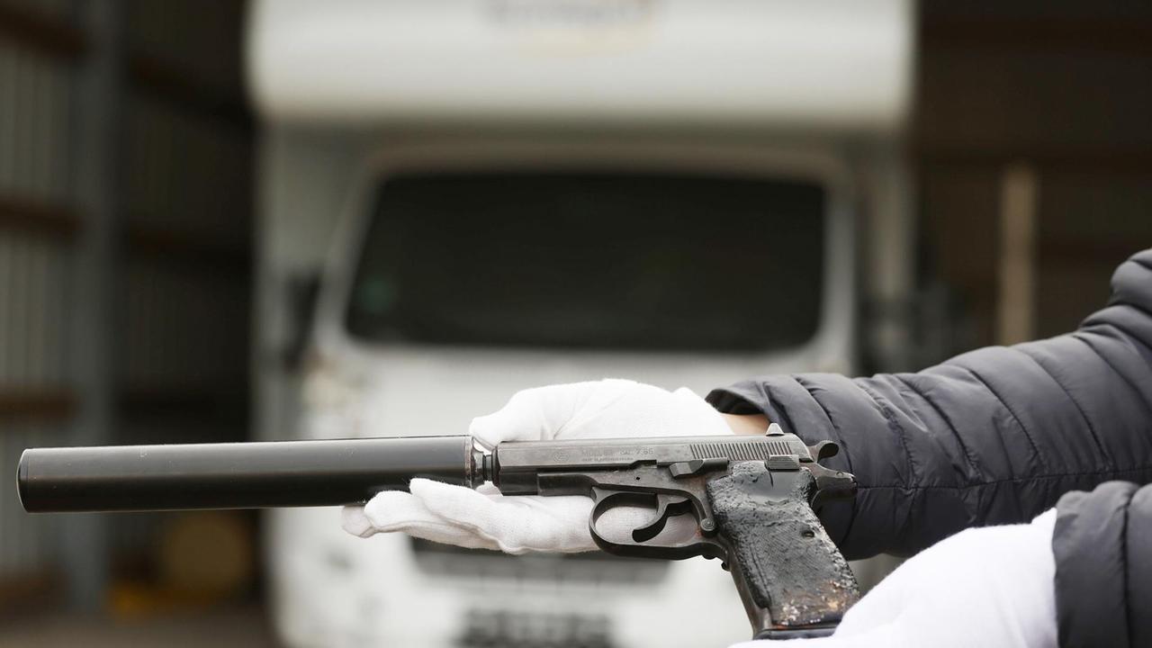 Ein Mitarbeiter des Bundeskriminalamtes hält eine Waffe