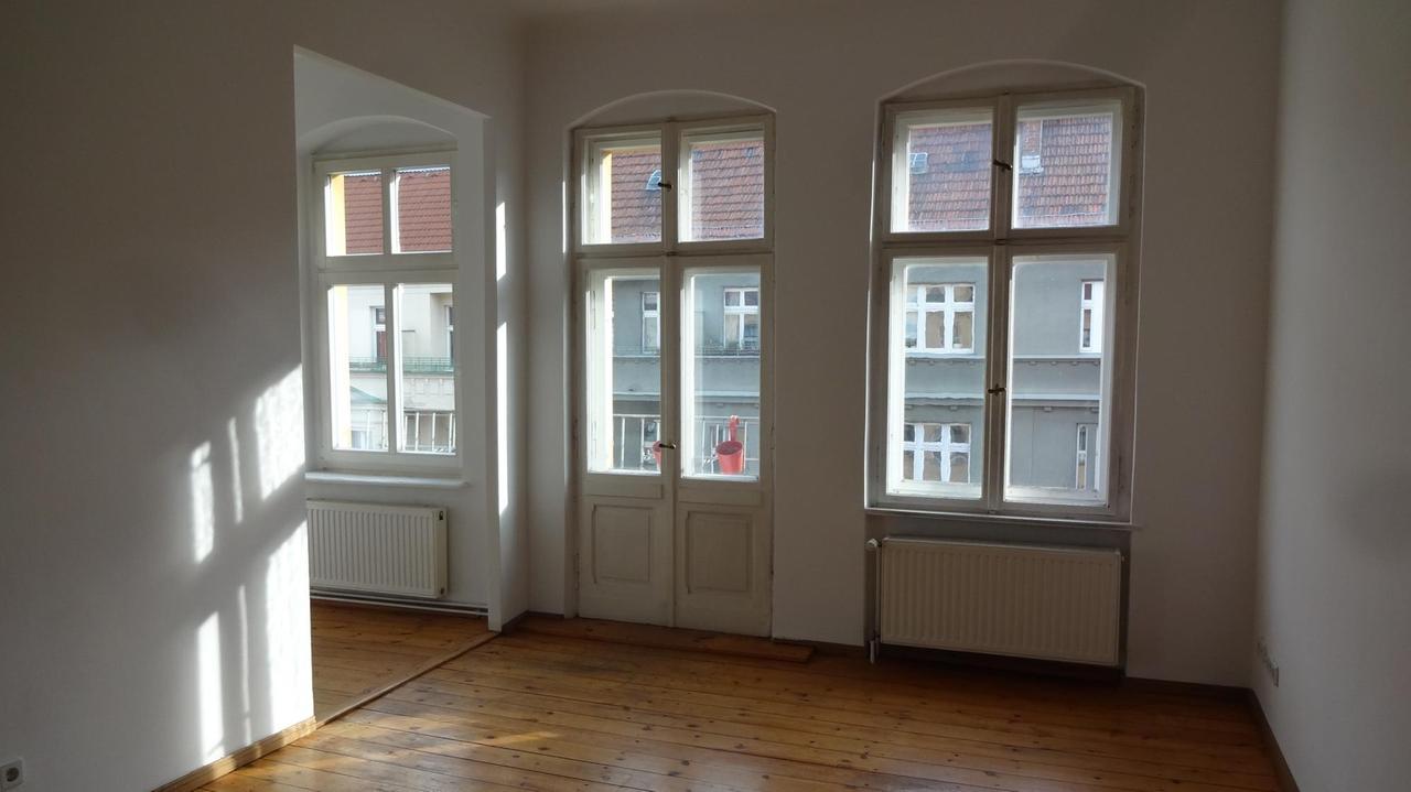 Leergeräumtes Zimmer mit Dielenboden und hohen Fenstern Leergeräumtes Zimmer mit Dielenboden und hohen Fenstern