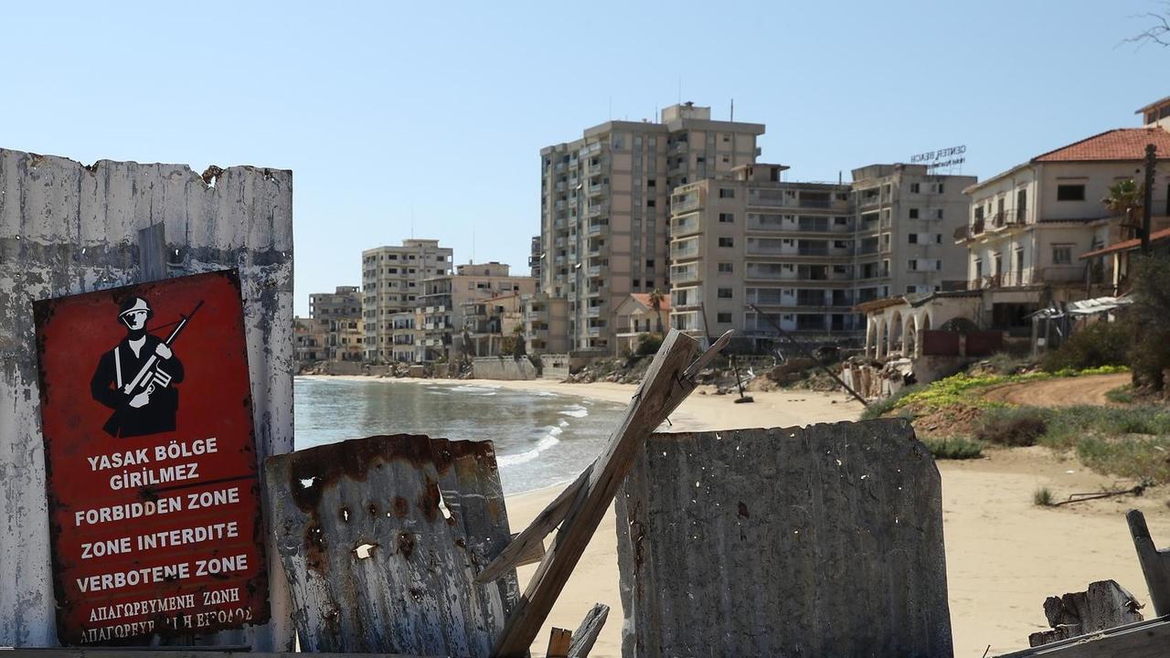 Ein Schild mit der Aufschrift "Verbotene Zone" vor einer Absperrung am Strand, dahinter sind die verfallenen Hotels des ehemaligen Touristenviertels Varosha in Famagusta zu sehen Ein Schild mit der Aufschrift "Verbotene Zone" vor einer Absperrung am Strand, dahinter sind die verfallenen Hotels des ehemaligen Touristenviertels Varosha in Famagusta zu sehen
