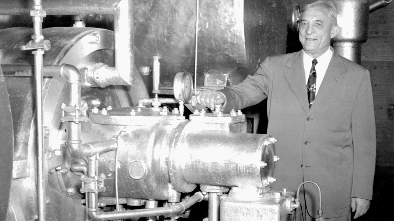 Willis Carrier steht neben einer aufwändig konstruierten Klimaanlage, die eher an eine große Industrieanlage erinnert. Willis Carrier steht neben einer aufwändig konstruierten Klimaanlage, die eher an eine große Industrieanlage erinnert.