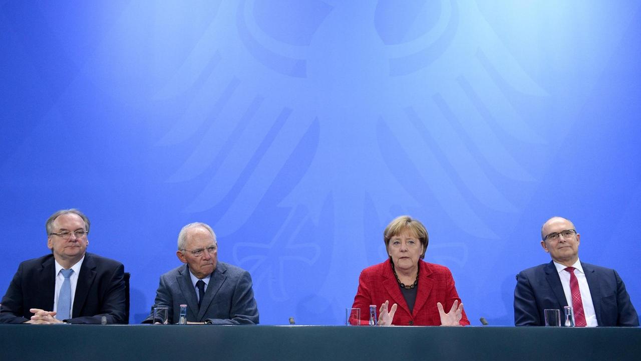 Die vier sitzen nebeneinander an einem Pult vor einer blauen Wand mit dem Bundesadler. Die vier sitzen nebeneinander an einem Pult vor einer blauen Wand mit dem Bundesadler.