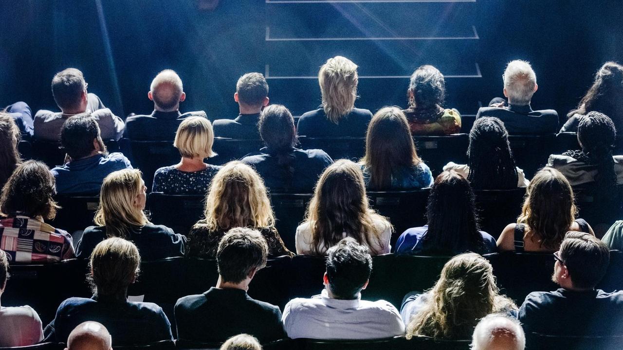 Publikum sitzt vor einer Bühne. Publikum sitzt vor einer Bühne.