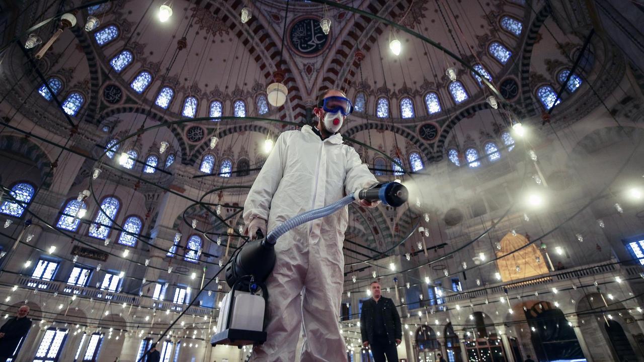 Ein Arbeiter in Schutzkleidung und mit Mundschutz desinfiziert die historische Fatih-Moschee in Istanbul. Ein Arbeiter in Schutzkleidung und mit Mundschutz desinfiziert die historische Fatih-Moschee in Istanbul.