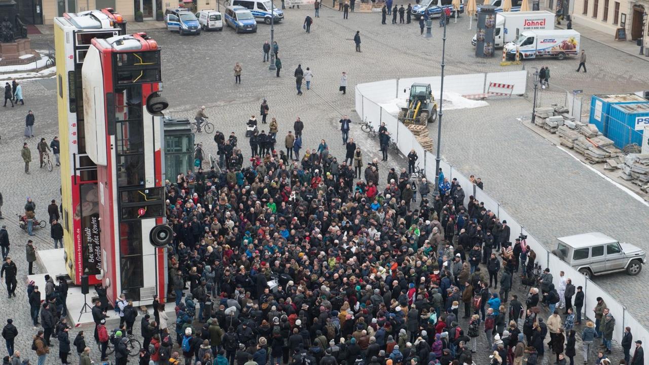 Demonstranten und Polizisten stehen am 07.02.2017 auf dem Neumarkt in Dresden (Sachsen) vor der Skulptur "Monument" des syrischen Künstlers Manaf Halbouni. Demonstranten und Polizisten stehen am 07.02.2017 auf dem Neumarkt in Dresden (Sachsen) vor der Skulptur "Monument" des syrischen Künstlers Manaf Halbouni.