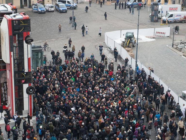 Demonstranten und Polizisten stehen am 07.02.2017 auf dem Neumarkt in Dresden (Sachsen) vor der Skulptur "Monument" des syrischen Künstlers Manaf Halbouni.