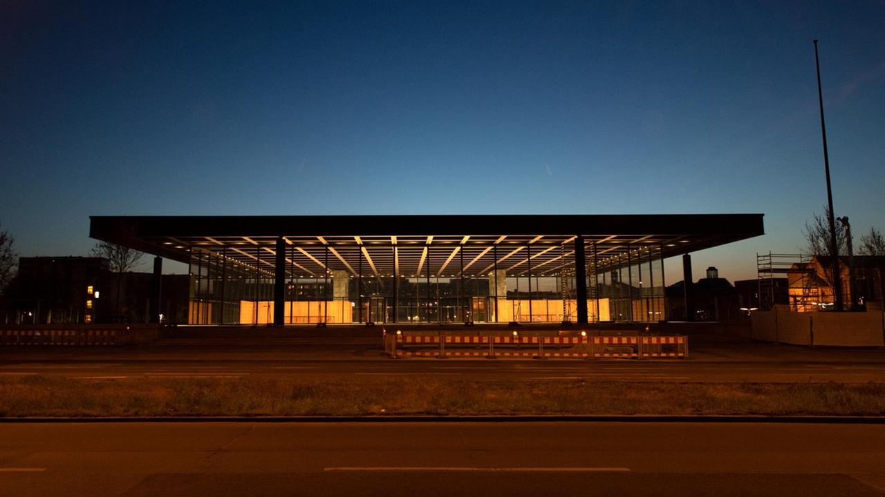 Das flache Gebäude mit einem großen Stahl-Dach und Glas-Wänden ist am Abend hell beleuchtet Das flache Gebäude mit einem großen Stahl-Dach und Glas-Wänden ist am Abend hell beleuchtet