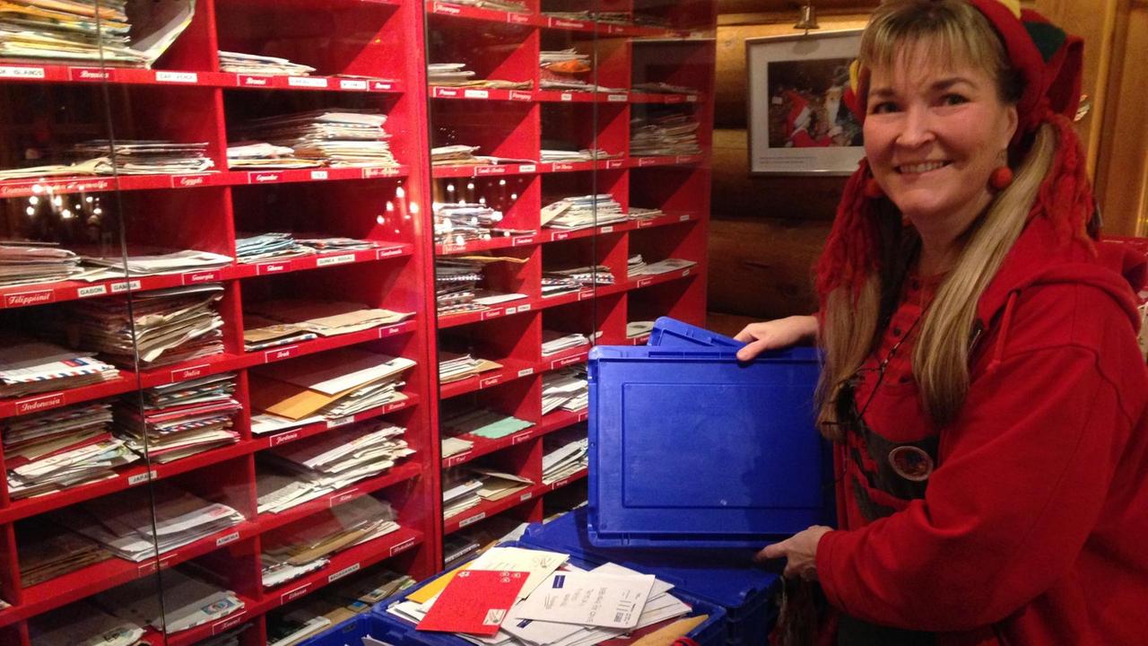 Postmitarbeiterin Riita zeigt volle Kisten mit Post für den Weihnachtsmann
