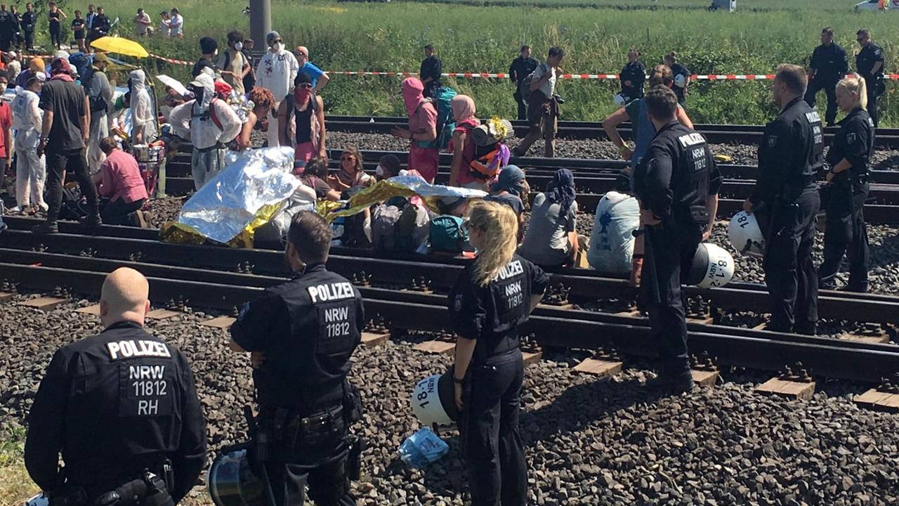 Polizisten stehen neben Bahngleisen, die von Umweltaktivisten besetzt wurden. Polizisten stehen neben Bahngleisen, die von Umweltaktivisten besetzt wurden.