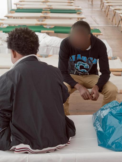 Aus Afrika stammende Flüchtlinge sitzen in einem Zelt einer Erstaufnahmeeinrichtung in Gießen.