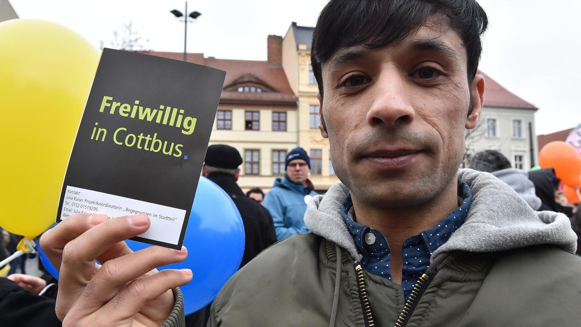 Ein Syrer zeigt bei der Demonstration von Flüchtlingen und Cottbusern unter dem Motto "Leben ohne Hass" eine Flyer mit der Aufschrift "Freiwillig in Cottbus". Ein Syrer zeigt bei der Demonstration von Flüchtlingen und Cottbusern unter dem Motto "Leben ohne Hass" eine Flyer mit der Aufschrift "Freiwillig in Cottbus".