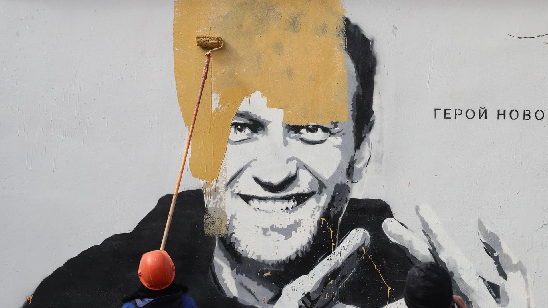 Ein Wandbild auf einem Gebäude in St. Petersburg, das den russischen Oppositionellen Alexej Nawalny zeigt mit dem Schriftzug "Der Held einer neuen Zeit", wird kurz nach seiner Entdeckung übermalt. Ein Wandbild auf einem Gebäude in St. Petersburg, das den russischen Oppositionellen Alexej Nawalny zeigt mit dem Schriftzug "Der Held einer neuen Zeit", wird kurz nach seiner Entdeckung übermalt.