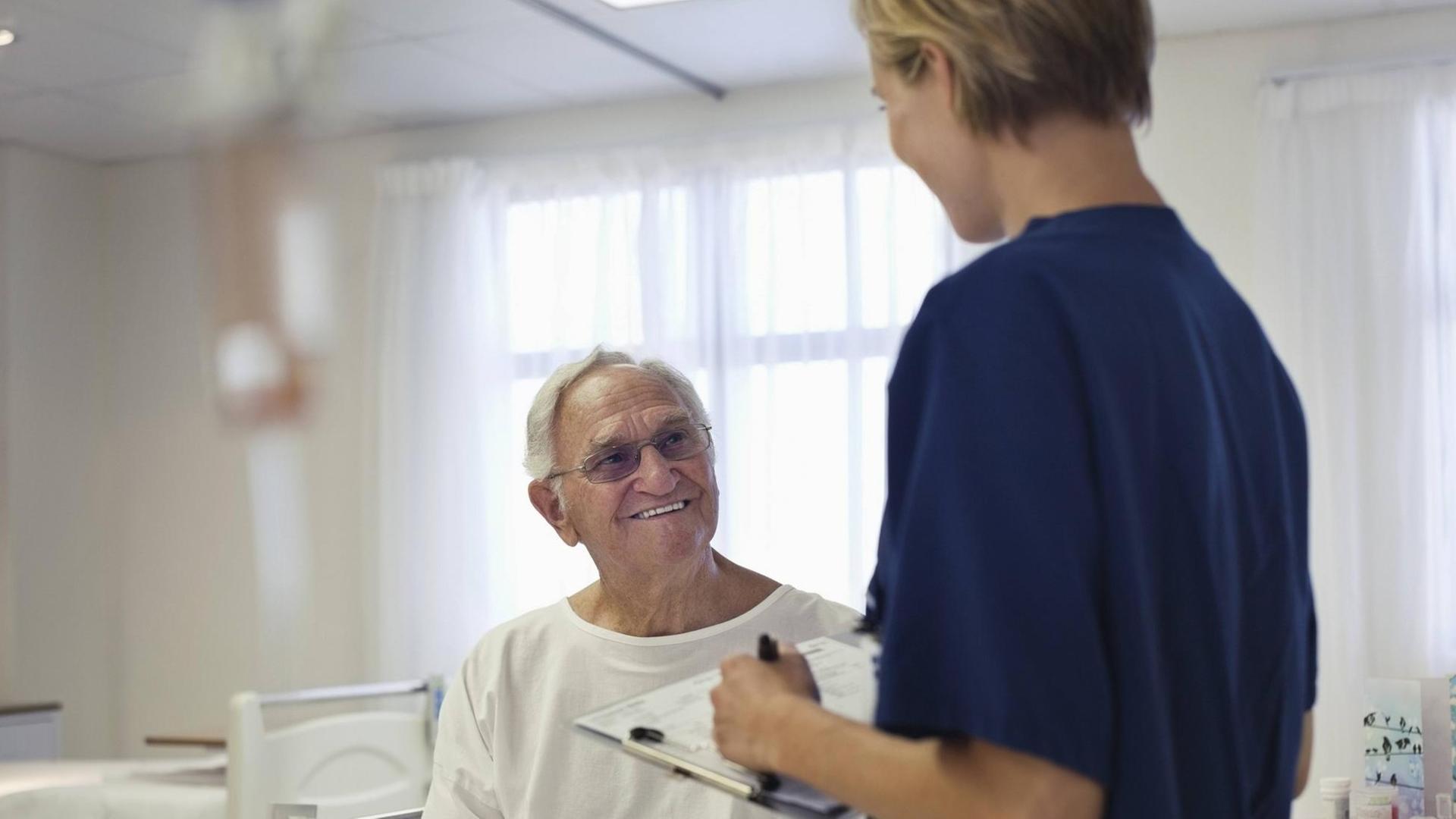 Eine Krankenpflegerin im Gespräch mit einem älteren Patienten Eine Krankenpflegerin im Gespräch mit einem älteren Patienten