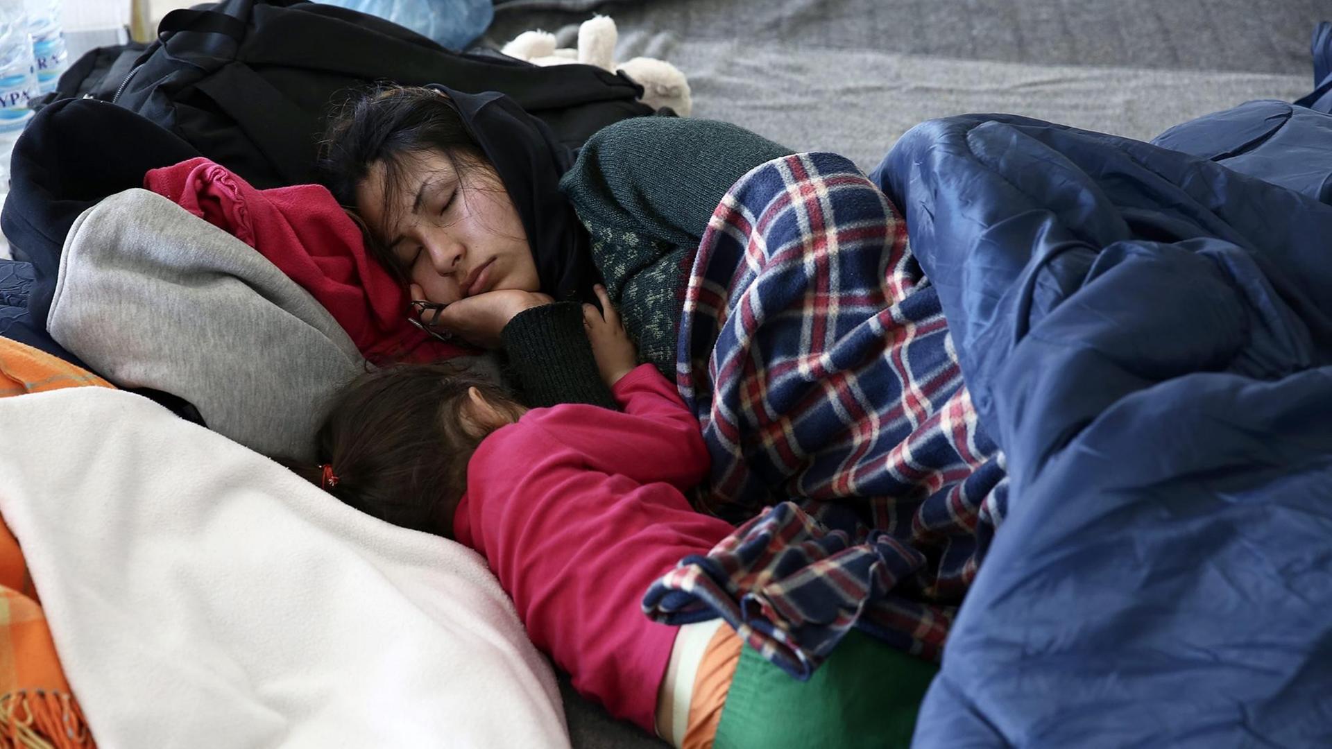 Eine junge Frau und ihr Kind schlafen in einem provisorischen Flüchtlingslager im alten Flughafen von Athen. Eine junge Frau und ihr Kind schlafen in einem provisorischen Flüchtlingslager im alten Flughafen von Athen.
