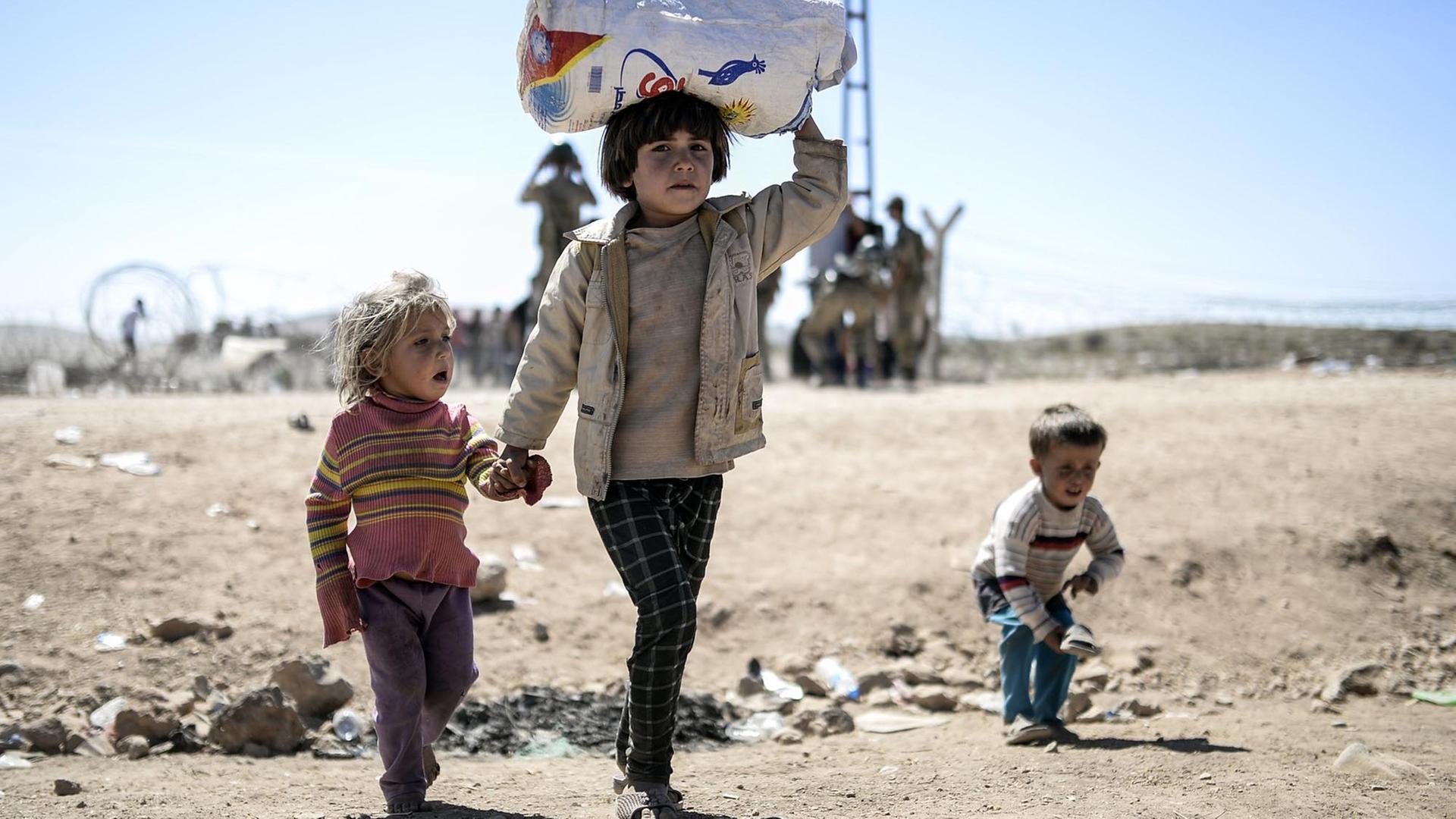 Syrische Kurden überqueren am 20. September 2014 die Grenze nahe der Stadt Suruc die Grenze von Syrien zur Türkei. Syrische Kurden überqueren am 20. September 2014 die Grenze nahe der Stadt Suruc die Grenze von Syrien zur Türkei.