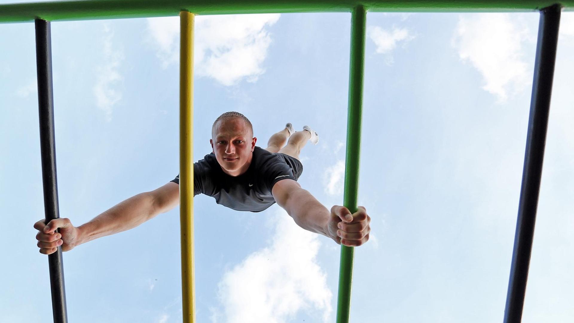 Ein junger Mann macht einen Handstand auf einem Klettergerüst. Ein junger Mann macht einen Handstand auf einem Klettergerüst.