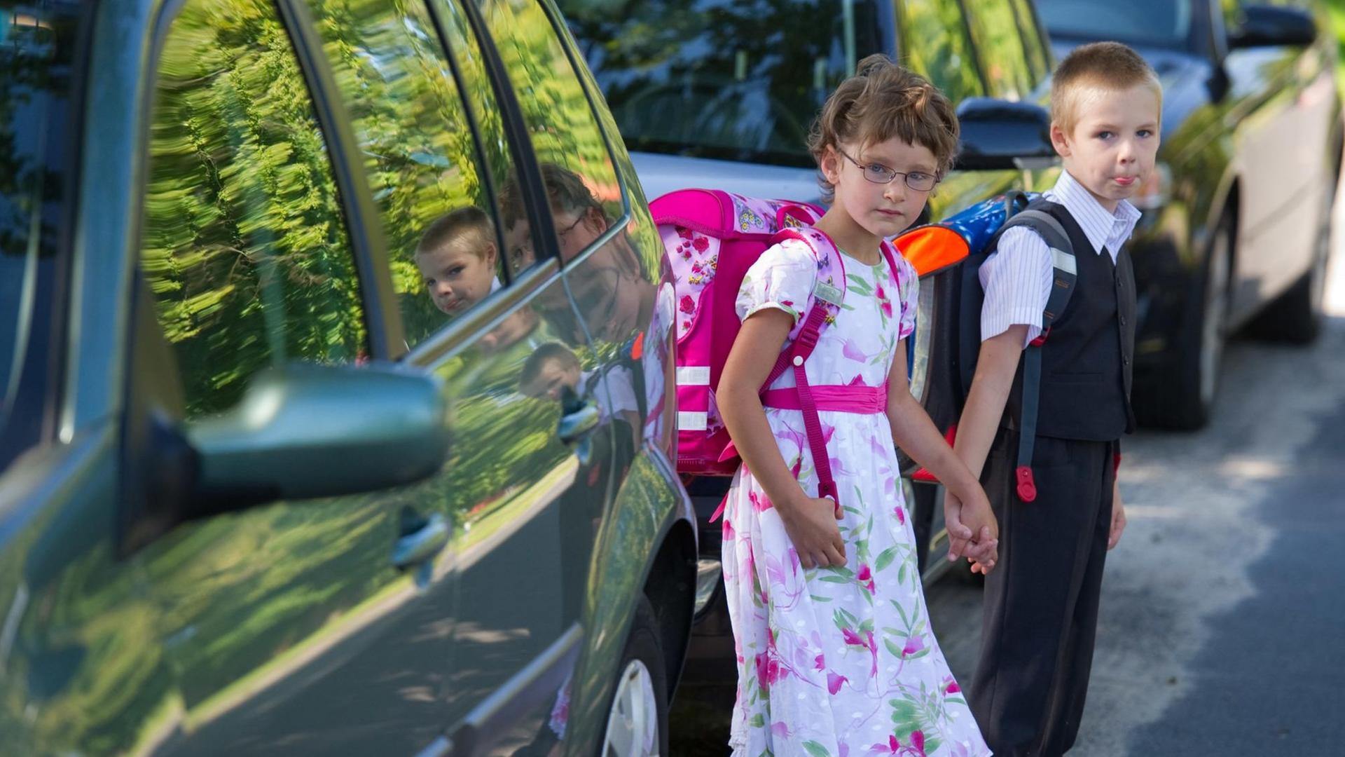 Zwei Erstklässler laufen zwischen zwei Autos durch. | picture alliance / dpa / Patrick Pleul Zwei Erstklässler laufen zwischen zwei Autos durch. | picture alliance / dpa / Patrick Pleul
