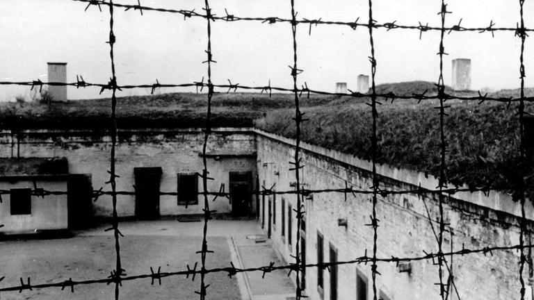 Blick durch Stacheldraht auf die Gebäude des 1941 von der SS errichteten Konzentrationslagers im tschechischen Theresienstadt. Blick durch Stacheldraht auf die Gebäude des 1941 von der SS errichteten Konzentrationslagers im tschechischen Theresienstadt.