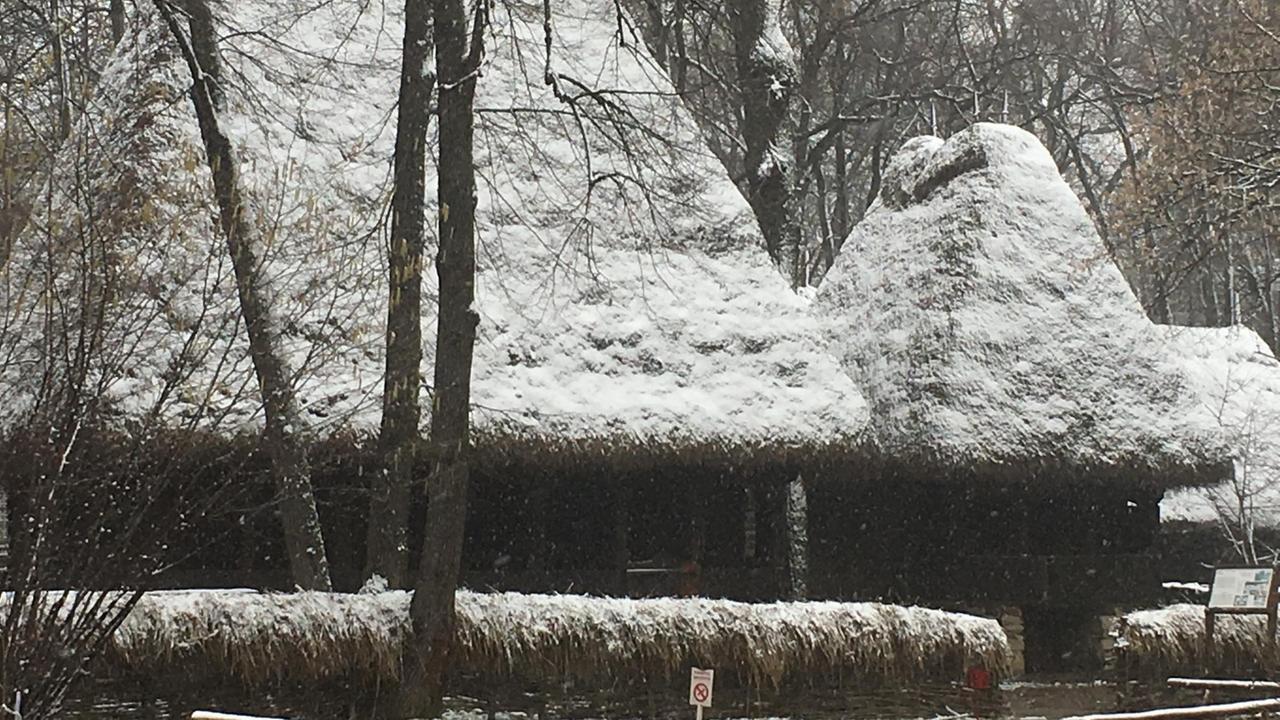Verschneite Holzhäuser im Bauernmuseum in der Nähe von Bukarest.