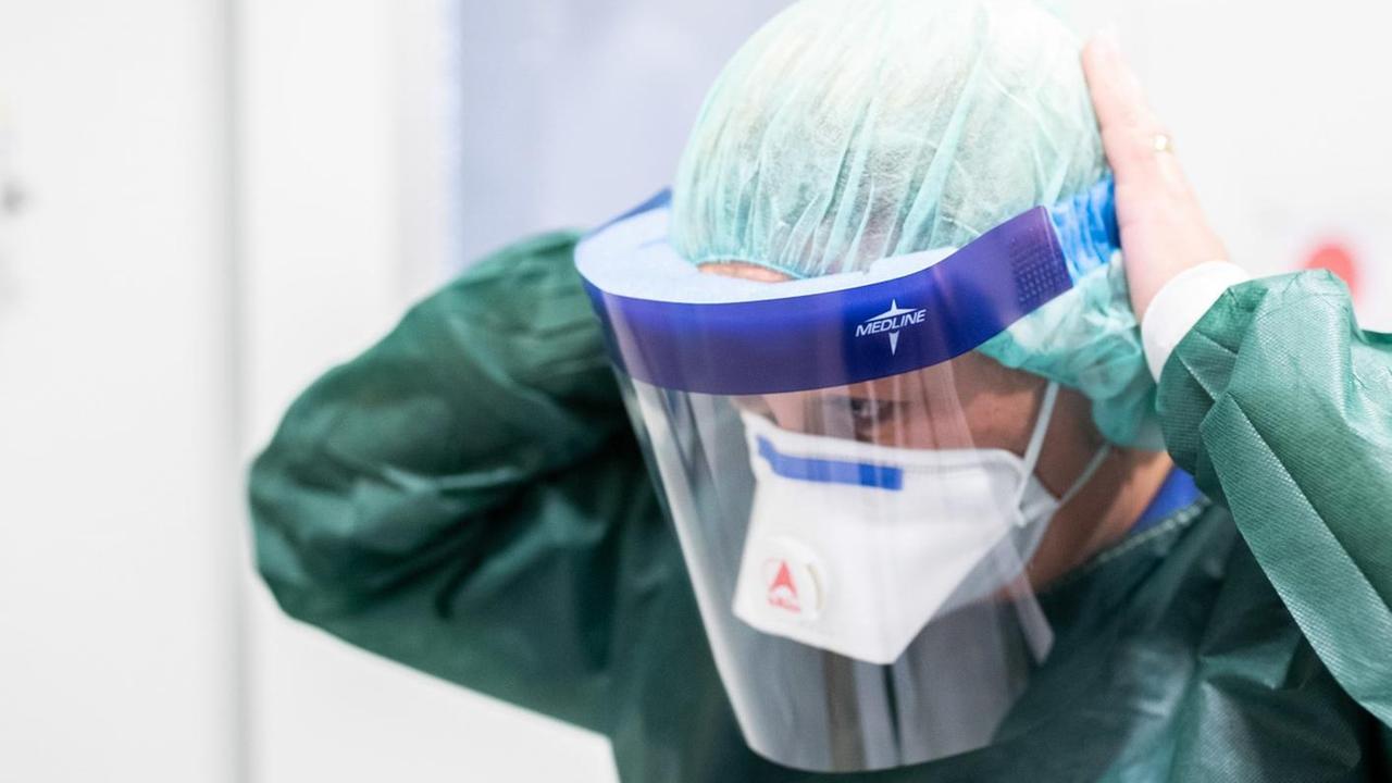 28.02.2020, Nordrhein-Westfalen, Essen: Canan Emcan, Stationsleiterin auf der Infektionsstation der Uniklinik Essen, steht in Schutzkleidung und mit einer Atemmaske in einer Schleuse und bekleidet sich mit einem Gesichtsschutz. Hier werden besonders schwere Fälle behandelt und hier könnten in Zukunft auch Coronavirus-Patienten untergebracht werden. Foto: Marcel Kusch/dpa | Verwendung weltweit 28.02.2020, Nordrhein-Westfalen, Essen: Canan Emcan, Stationsleiterin auf der Infektionsstation der Uniklinik Essen, steht in Schutzkleidung und mit einer Atemmaske in einer Schleuse und bekleidet sich mit einem Gesichtsschutz. Hier werden besonders schwere Fälle behandelt und hier könnten in Zukunft auch Coronavirus-Patienten untergebracht werden. Foto: Marcel Kusch/dpa | Verwendung weltweit