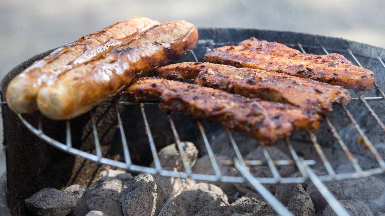 Würstchen und Bauchspeck auf einem Holzkohlegrill Würstchen und Bauchspeck auf einem Holzkohlegrill