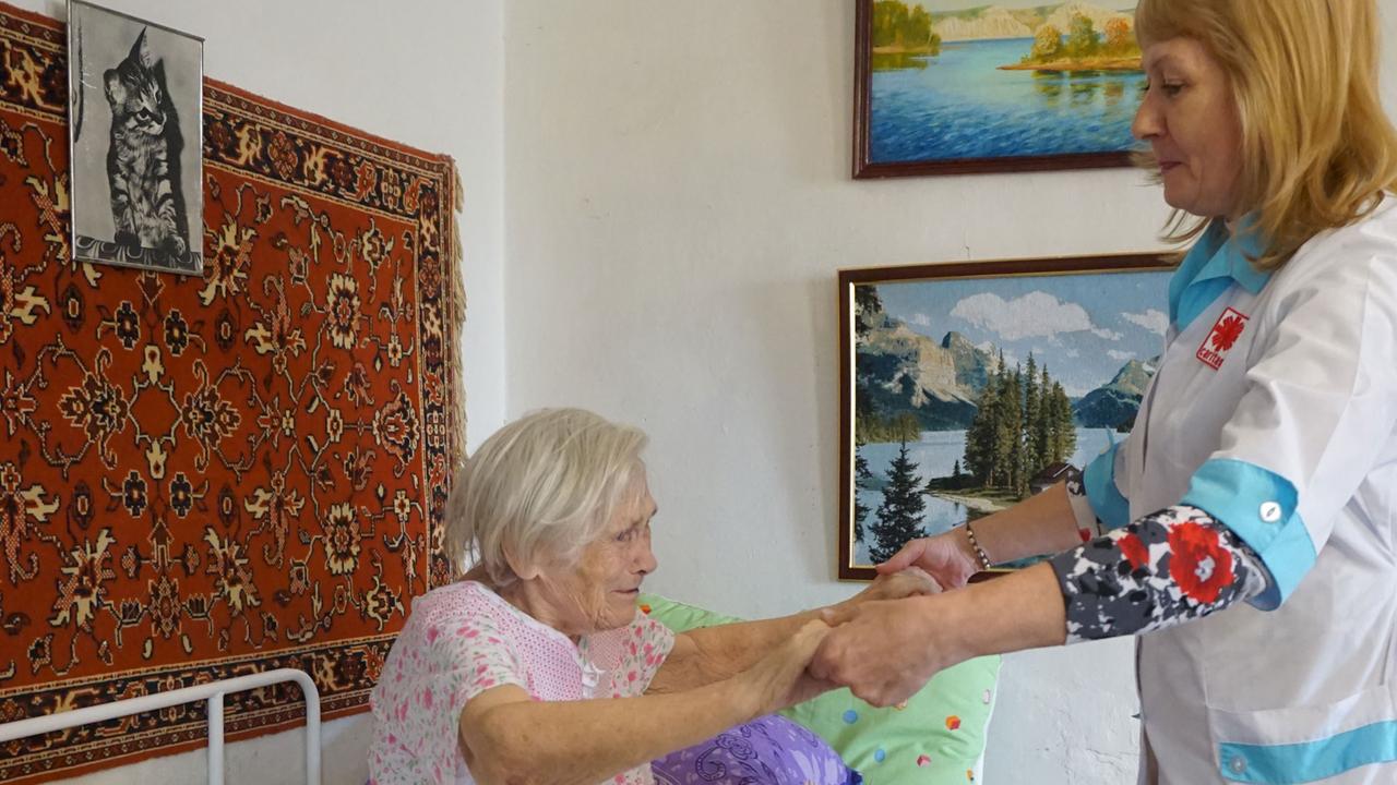 Ambulante Pflege der Caritas in Marx: eine Pflegerin hilft einer alten Frau beim Aufstehen.
