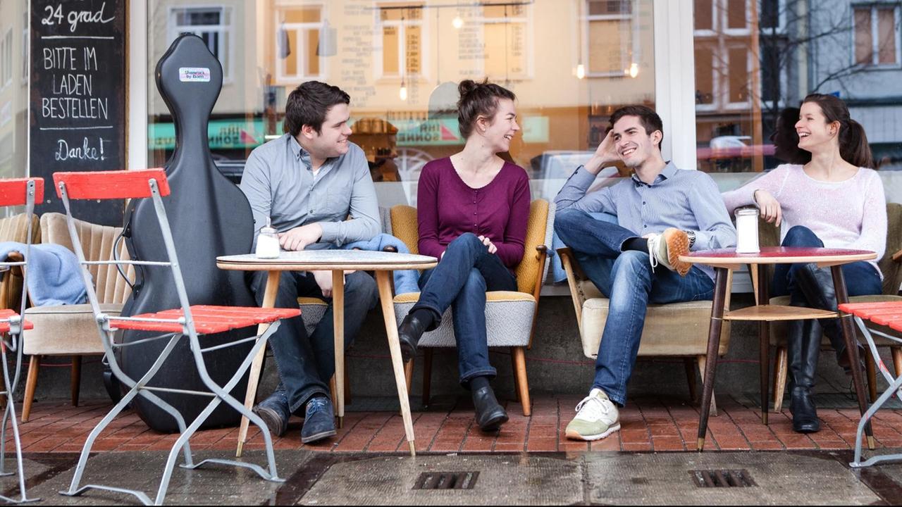 Die Quartettmitglieder sitzen in Jeans in einem Straßenkaffee. Die Quartettmitglieder sitzen in Jeans in einem Straßenkaffee.