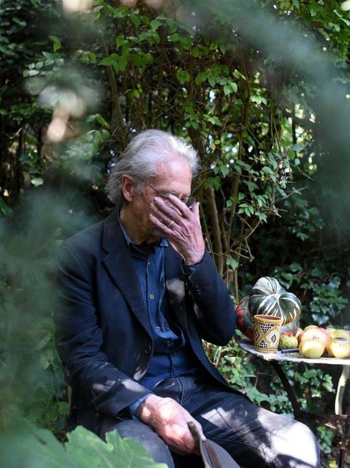 Der Autor Peter Handke in einem Garten mit der Hand vor den Augen