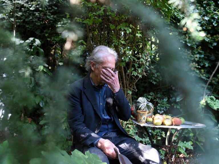 Der Autor Peter Handke in einem Garten mit der Hand vor den Augen