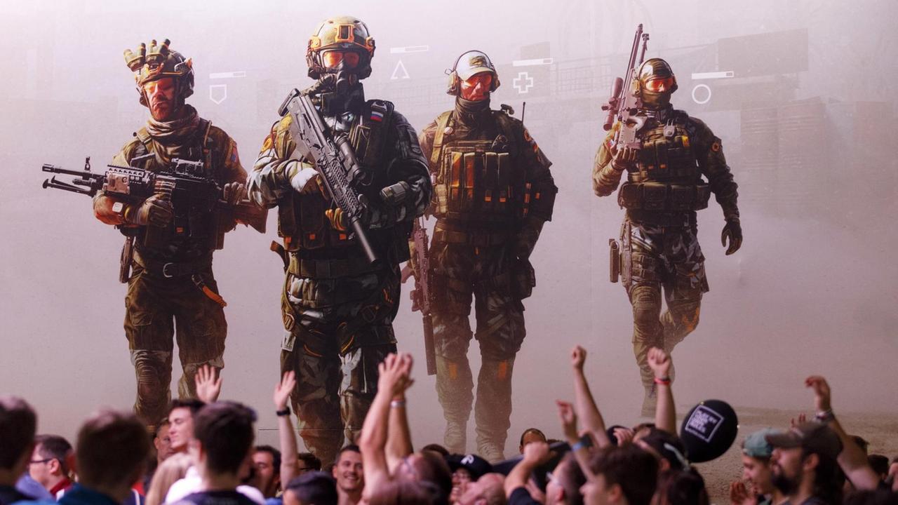 Junge Männer recken die Hände in die Luft vor einem Werbeplakat des Egoshooters Caliber. Junge Männer recken die Hände in die Luft vor einem Werbeplakat des Egoshooters Caliber.