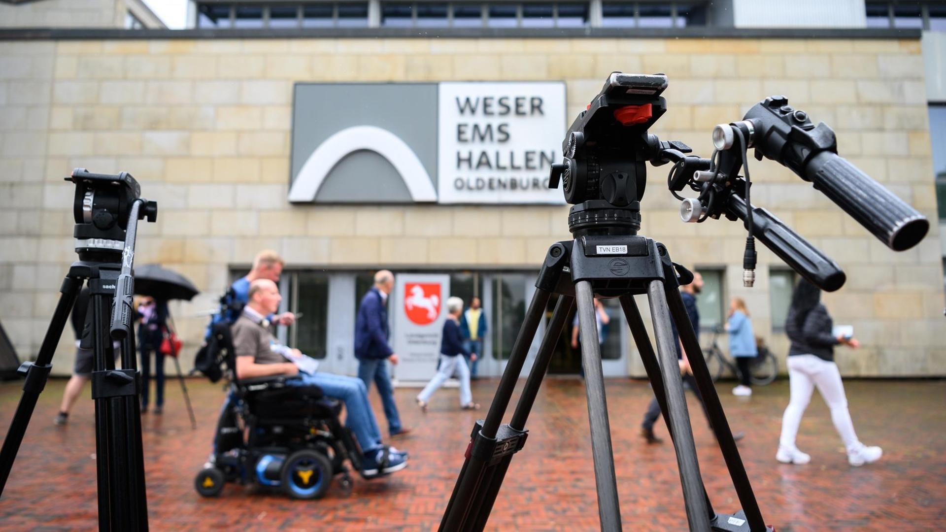 Personen sind während des letzten Prozesstages des Patientenmörders Niels Högel vor der Weser-Ems-Halle (Oldenburg in Niedersachsen) hinter zwei Filmstativen Personen sind während des letzten Prozesstages des Patientenmörders Niels Högel vor der Weser-Ems-Halle (Oldenburg in Niedersachsen) hinter zwei Filmstativen