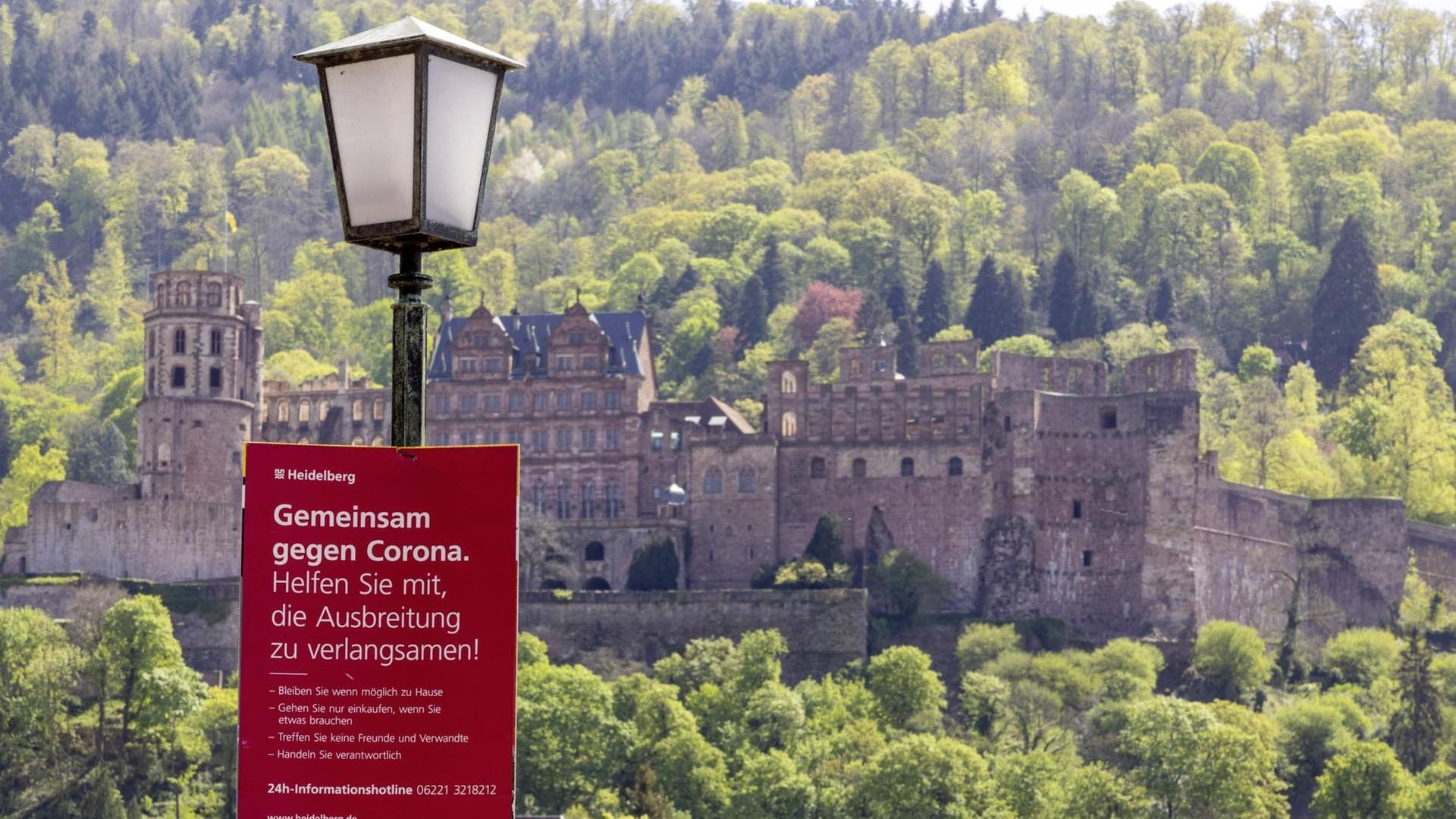 Ein Corona-Warnschild an der Alten Brücke vor dem Heidelberger Schloss. Ein Corona-Warnschild an der Alten Brücke vor dem Heidelberger Schloss.