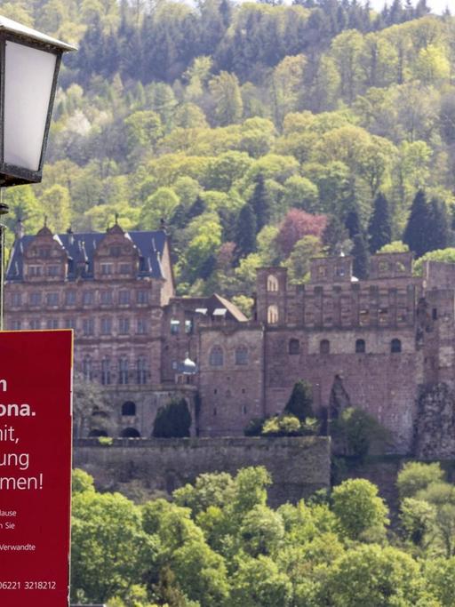 Ein Corona-Warnschild an der Alten Brücke vor dem Heidelberger Schloss.