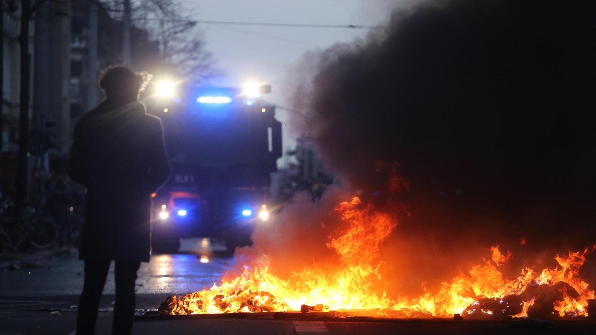 Ein Wasserwerfer steht vor einer brennenden Barrikade bei Auseinandersetzungen zwischen linken Gegendemonstranten und der Polizei am 12.12.2015 bei einer Demonstration der Partei "Die Rechte" in Leipzig (Sachsen) Ein Wasserwerfer steht vor einer brennenden Barrikade bei Auseinandersetzungen zwischen linken Gegendemonstranten und der Polizei am 12.12.2015 bei einer Demonstration der Partei "Die Rechte" in Leipzig (Sachsen)