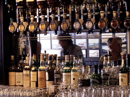Die Whisky-Auswahl einer Bar in Oban in Schottland: Dutzende Whisky-Flaschen und zahlreiche Gläser sind zu sehen.