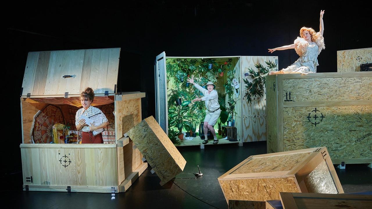 Bühne auf der große Holzcontainer stehen aus denen Schauspieler schauen.