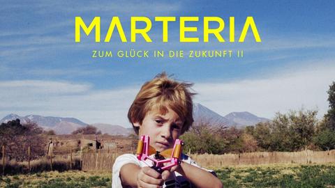 Auf dem Cover "Zum Glück in die Zukunft II" von Marteria spannt ein Junge auf einer Wiese eine Schleuder und zielt auf den Betrachter.