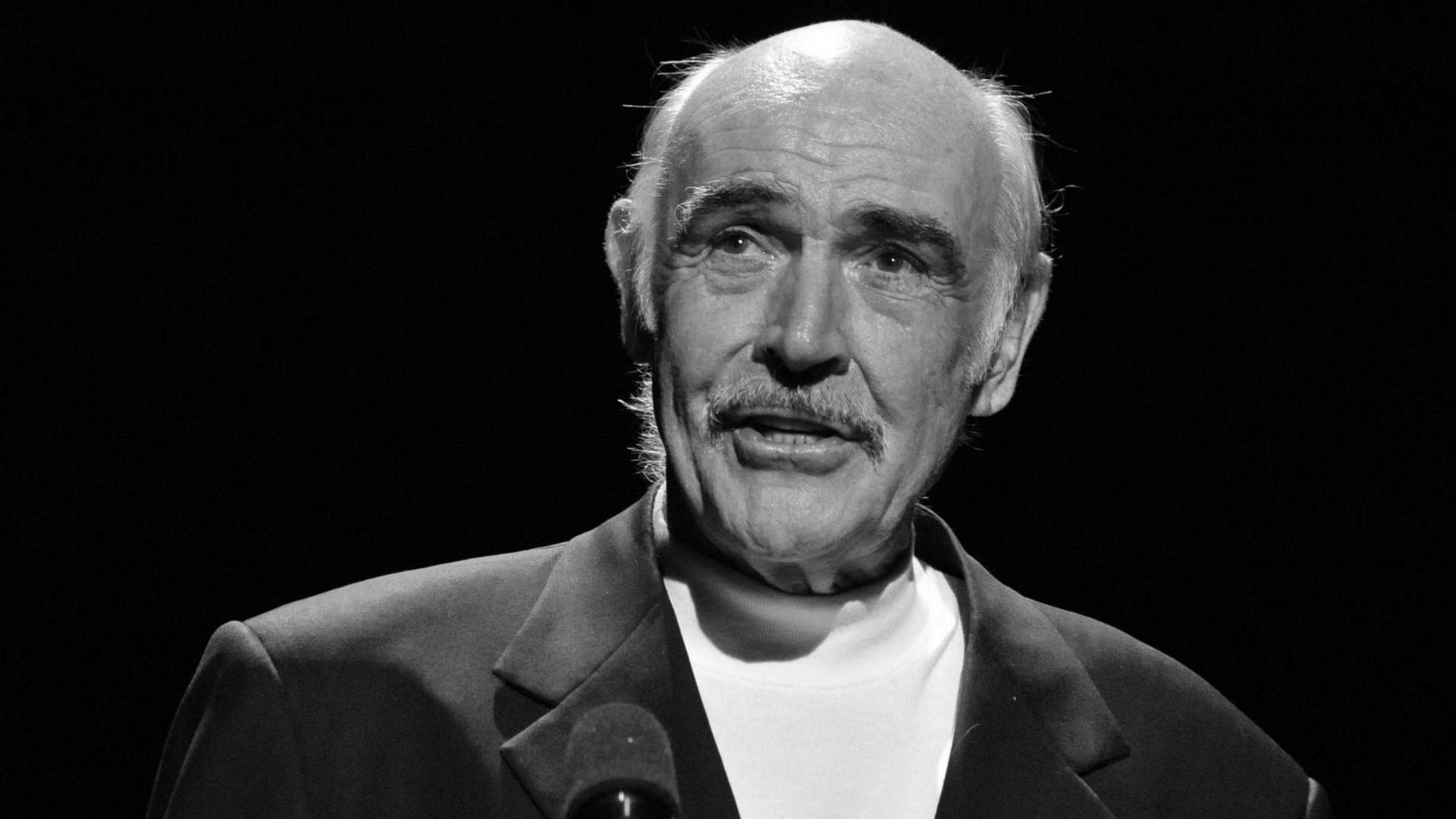 Sean Connery lächelt und spricht in ein Mikrofon Sean Connery lächelt und spricht in ein Mikrofon