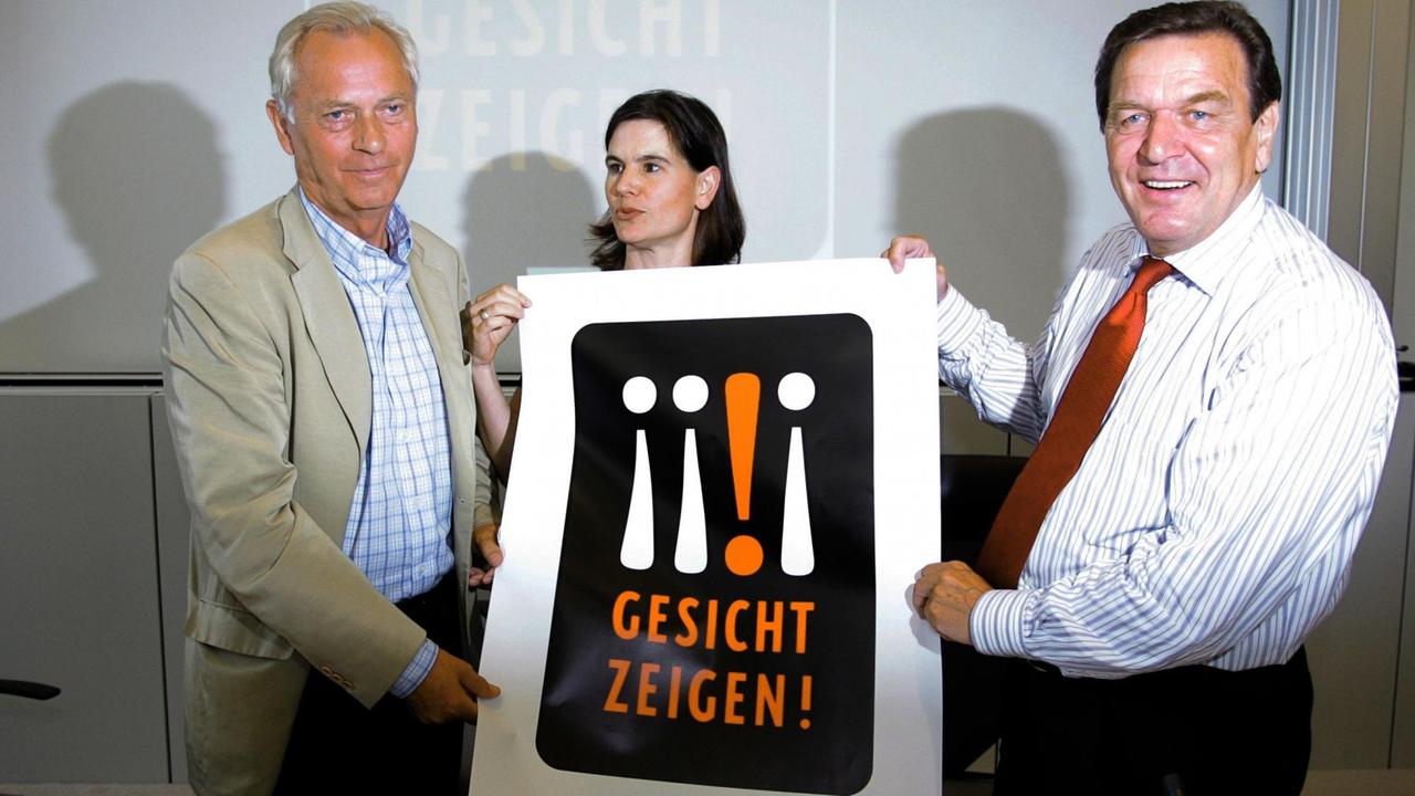 Gerhard Schröder, Uwe-Karsten Heye und Sophia Oppermann mit einem Plakat mit der Aufschrift "Gesicht zeigen!" Gerhard Schröder, Uwe-Karsten Heye und Sophia Oppermann mit einem Plakat mit der Aufschrift "Gesicht zeigen!"