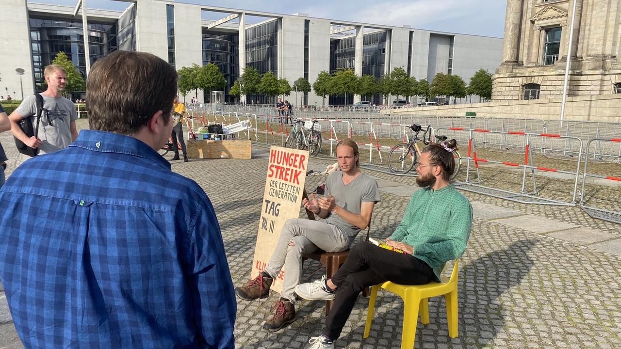 Simon Helmstedt und Jacob Heinze warten auf Stühlen darauf, dass die Kanzlerkandidat*innen mit ihnen sprechen. 