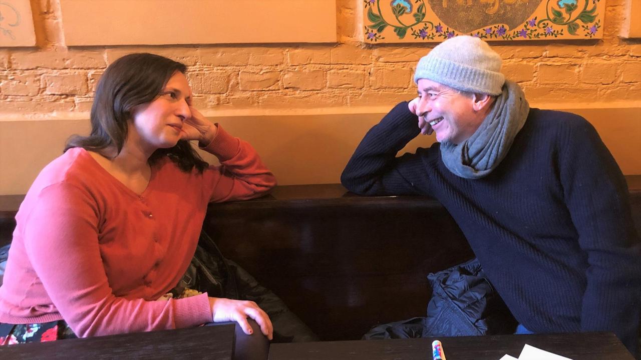 Andreas Toelke und Caro Korneli sitzen sich gegenüber und blicken sich in die Augen. Andreas Toelke und Caro Korneli sitzen sich gegenüber und blicken sich in die Augen.