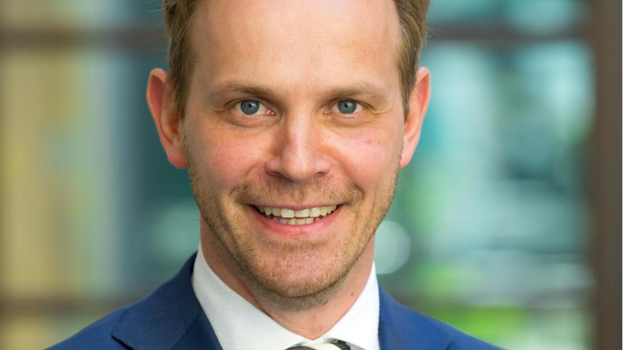 Ein Mann in blauem Anzug lacht in die Kamera. Ein Mann in blauem Anzug lacht in die Kamera.
