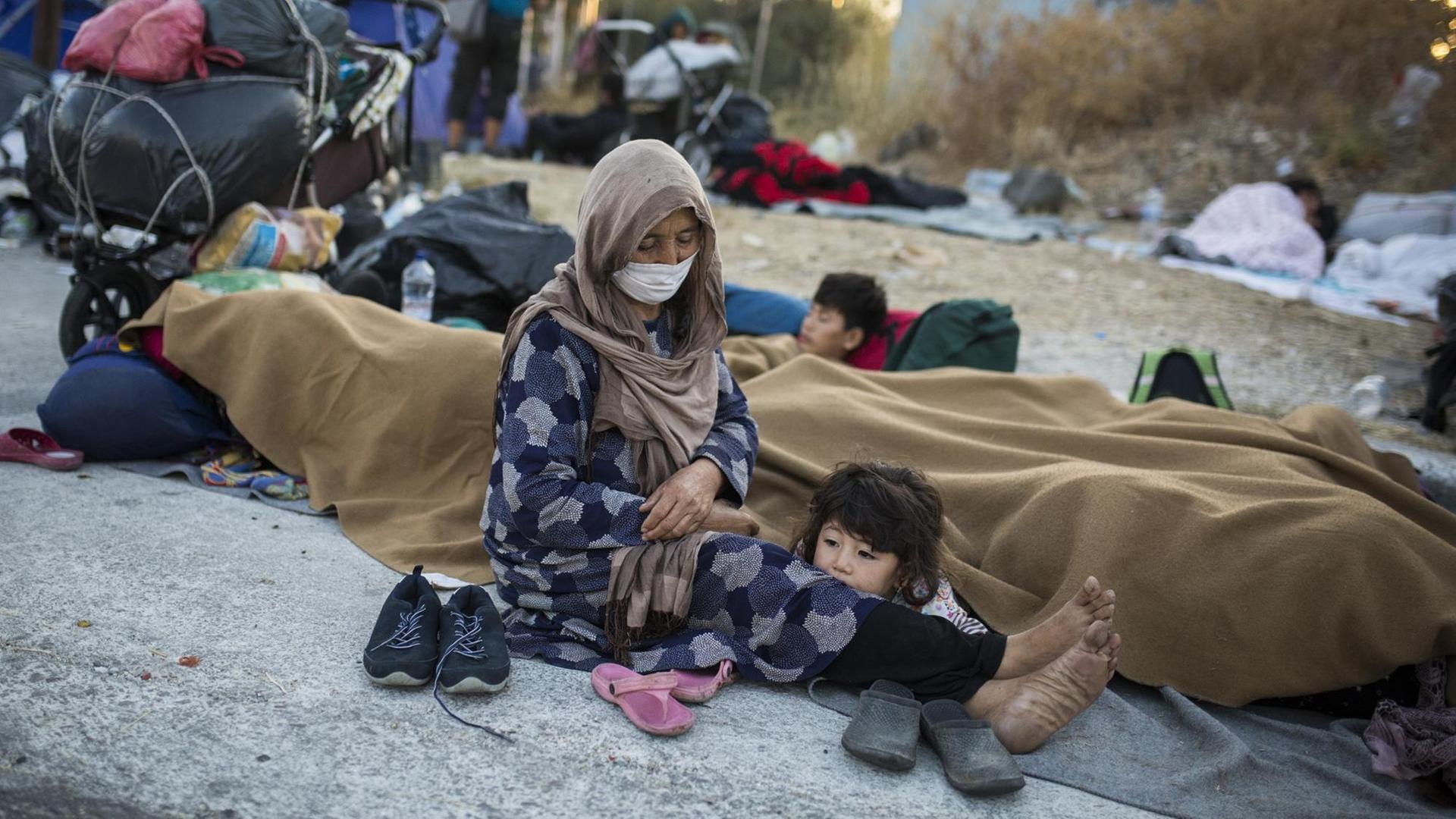 Eine Frau mit ihren Kindern sitzt am Rande einer Straße in der Nähe des ausgebrannten Flüchtlingslagers Moria. Eine Frau mit ihren Kindern sitzt am Rande einer Straße in der Nähe des ausgebrannten Flüchtlingslagers Moria.