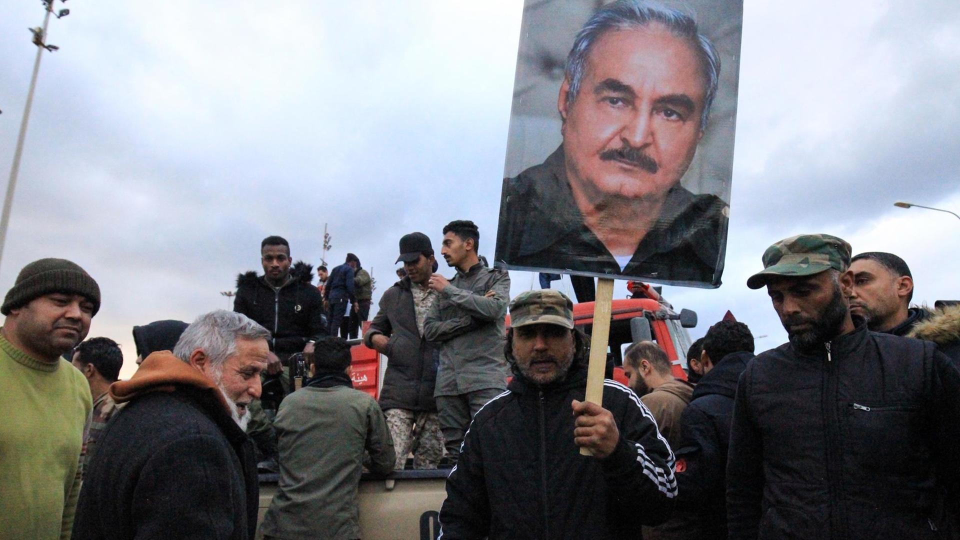 Das Foto zeigt Menschen in Bengasi/Libyen, die ein Plakat mit dem Konterfei von General Haftar hochhalten. Das Foto zeigt Menschen in Bengasi/Libyen, die ein Plakat mit dem Konterfei von General Haftar hochhalten.