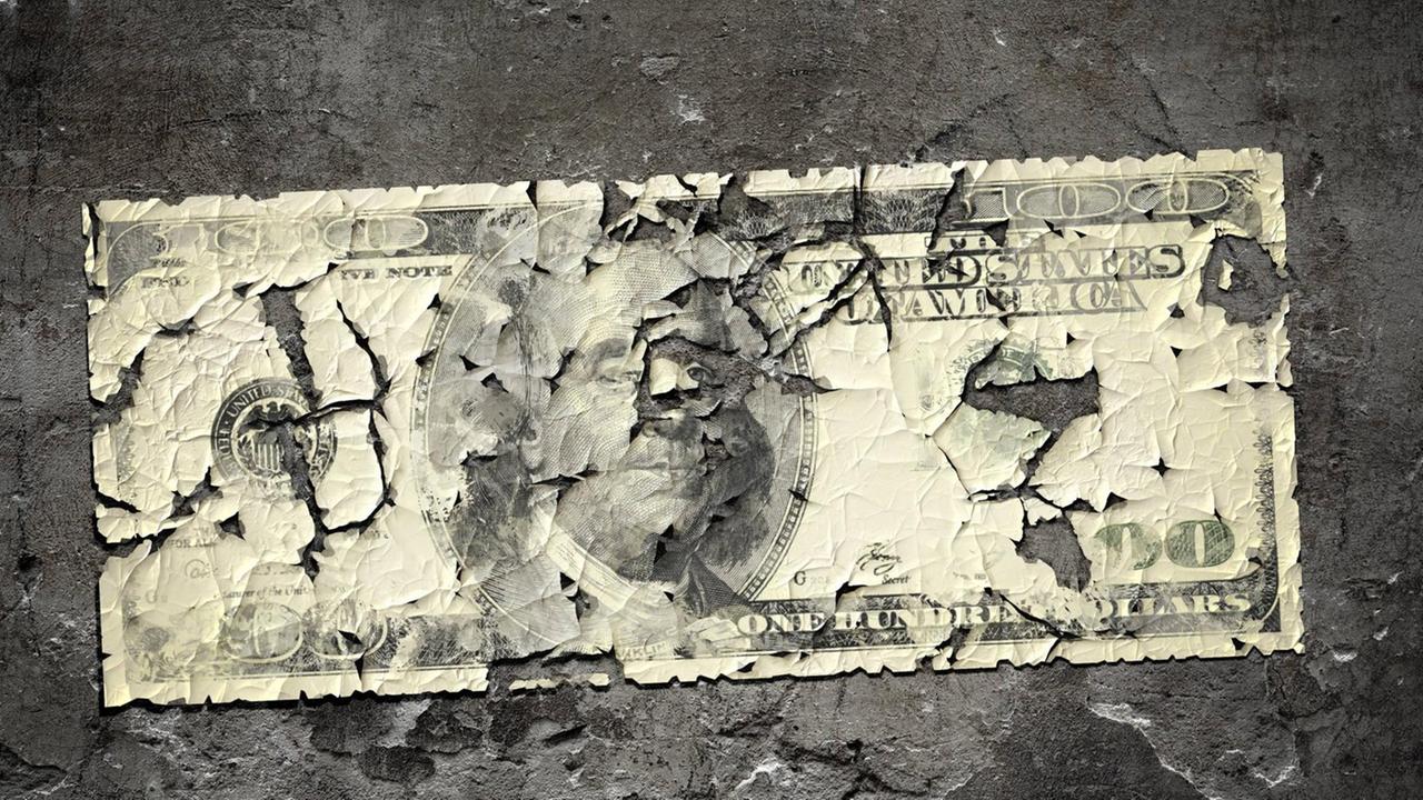Eine Computergrafik von einem 100-Dollar-Schein mit vielen Rissen vor einer grauen Betonwand.