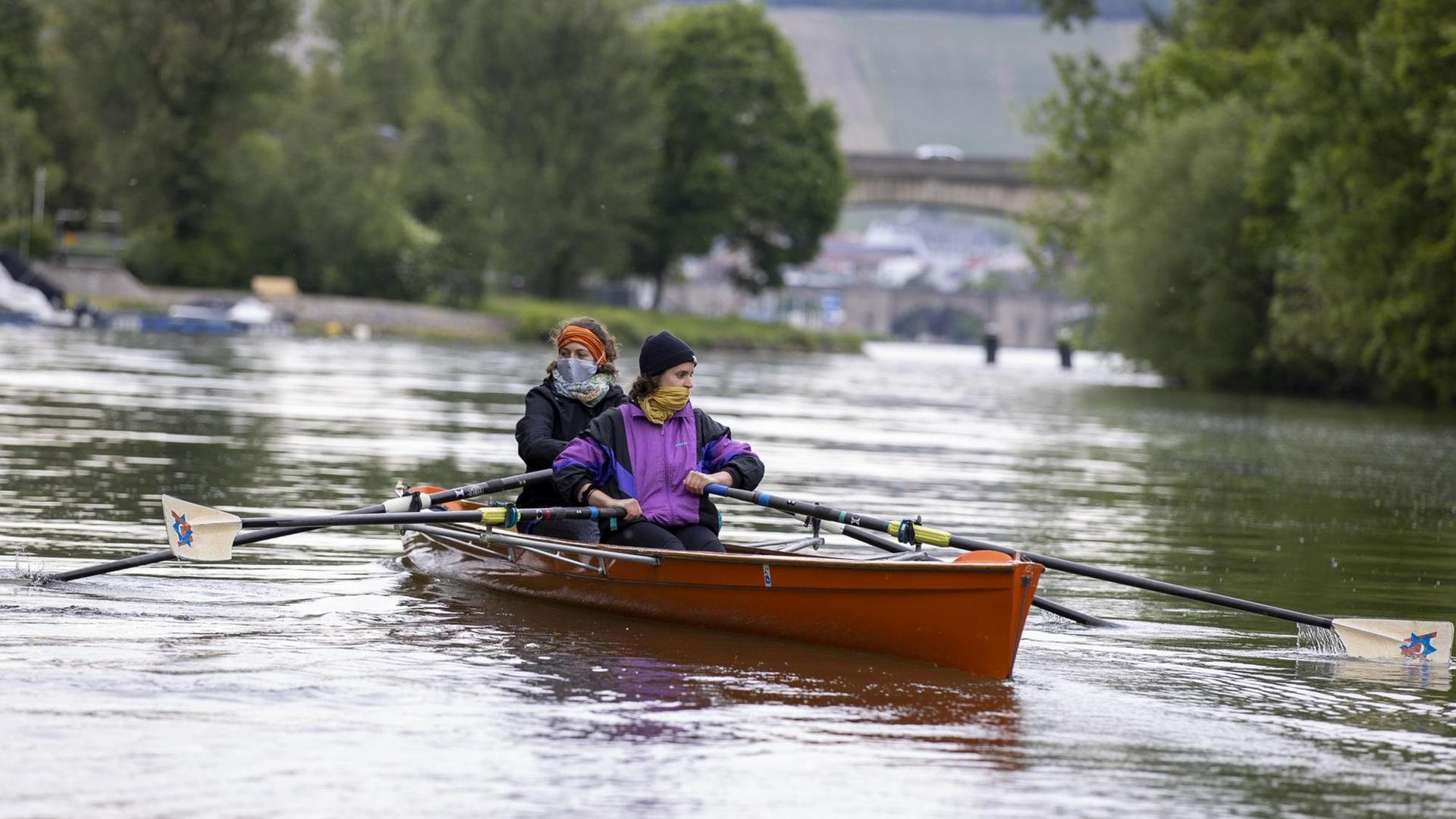 Zwei Ruderinnen mit Mundbedeckung in einem Ruderboot in Würzburg. Zwei Ruderinnen mit Mundbedeckung in einem Ruderboot in Würzburg.