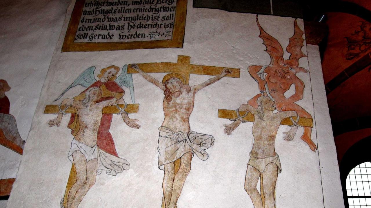 Die Kreuzigungsszene zeigt Jesus von Nazaret und die beiden Schächer am Kreuz, darüber ein Engel und ein Teufel