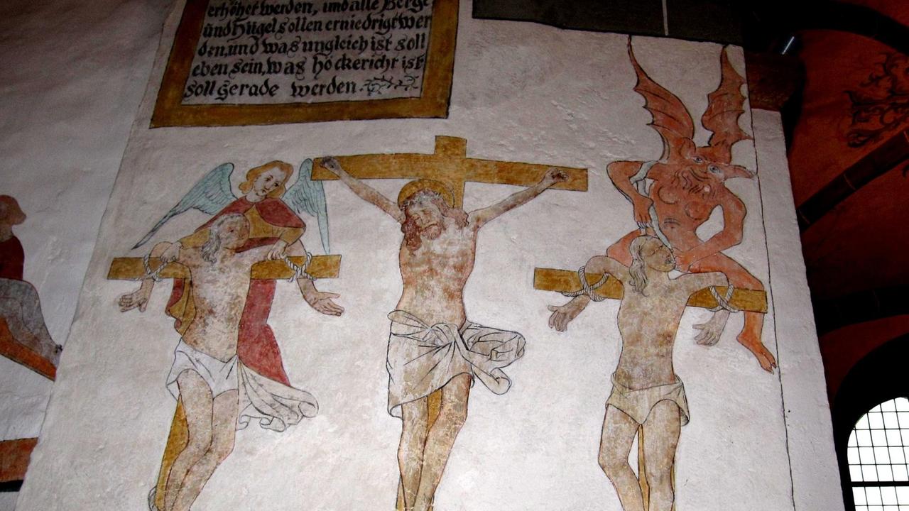Die Kreuzigungsszene zeigt Jesus von Nazaret und die beiden Schächer am Kreuz, darüber ein Engel und ein Teufel Die Kreuzigungsszene zeigt Jesus von Nazaret und die beiden Schächer am Kreuz, darüber ein Engel und ein Teufel