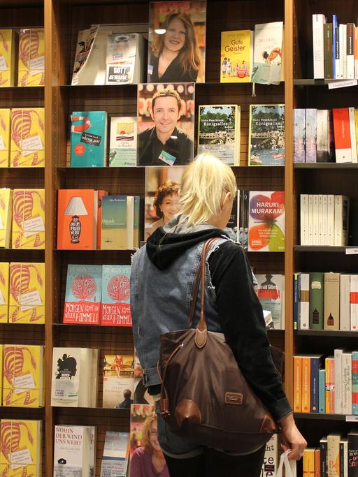 Eine junge Frau steht unschlüssig vor Bücherregalen in einer Buchhandlung