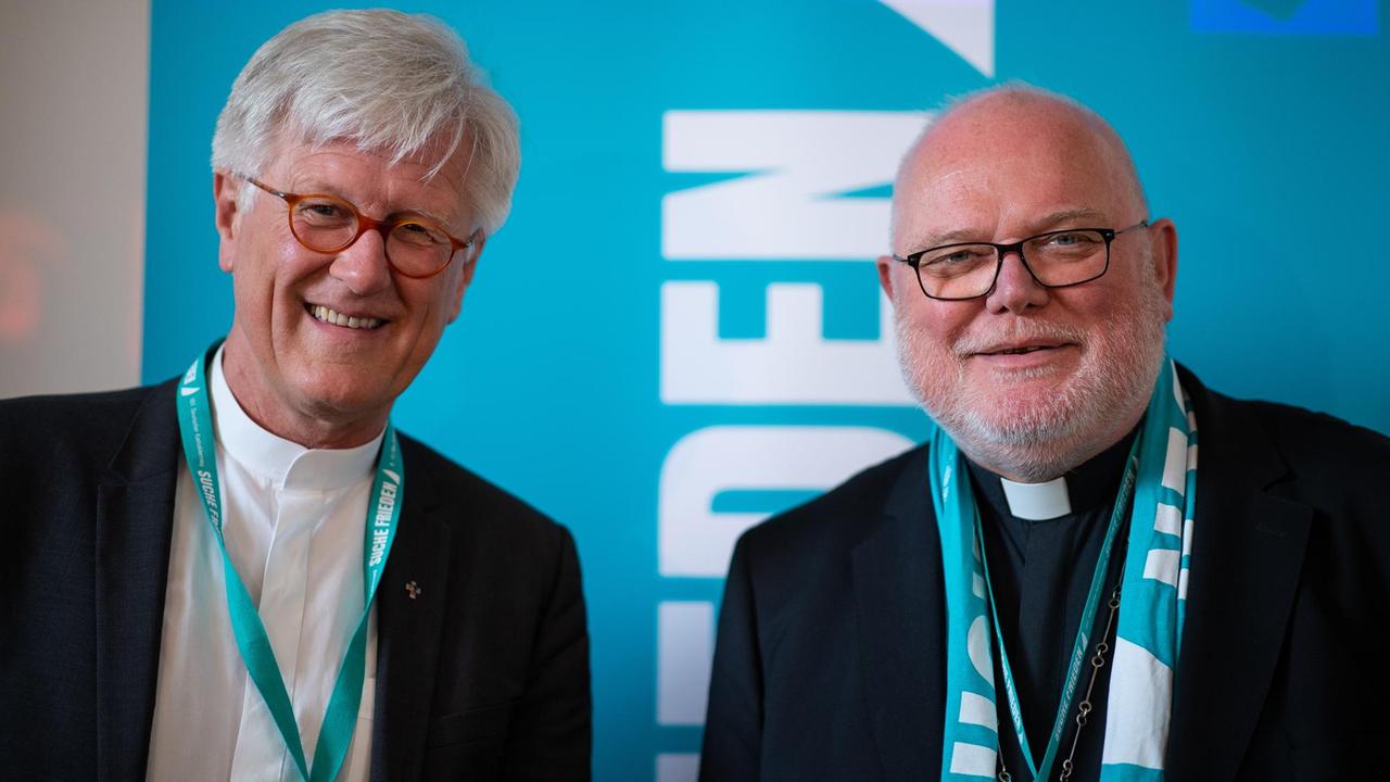 11.05.2018, Nordrhein-Westfalen, Münster: Kardinal Reinhard Marx (r), Vorsitzender der Deutschen Bischofskonferenz und Heinrich Bedford-Strohm, Ratsvorsitzender der Evangelischen Kirche in Deutschland, stehen vor der Podiumsdiskussion «Ökumene nach 2017 - Aufbruchs- oder Katerstimmung?» auf der Bühne. Der Katholikentag (vom 09.05. - 13.05.2018) ist das größte Laientreffen der katholischen Kirche in Deutschland und steht unter dem Motto «Suche Frieden». Veranstalter ist das Zentralkomitee der deutschen Katholiken (ZdK). Foto: Guido Kirchner/dpa | Verwendung weltweit 11.05.2018, Nordrhein-Westfalen, Münster: Kardinal Reinhard Marx (r), Vorsitzender der Deutschen Bischofskonferenz und Heinrich Bedford-Strohm, Ratsvorsitzender der Evangelischen Kirche in Deutschland, stehen vor der Podiumsdiskussion «Ökumene nach 2017 - Aufbruchs- oder Katerstimmung?» auf der Bühne. Der Katholikentag (vom 09.05. - 13.05.2018) ist das größte Laientreffen der katholischen Kirche in Deutschland und steht unter dem Motto «Suche Frieden». Veranstalter ist das Zentralkomitee der deutschen Katholiken (ZdK). Foto: Guido Kirchner/dpa | Verwendung weltweit